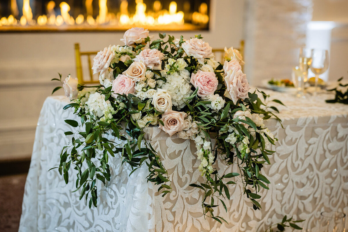 Elegant floral arrangement with pink and white roses on a white patterned tablecloth