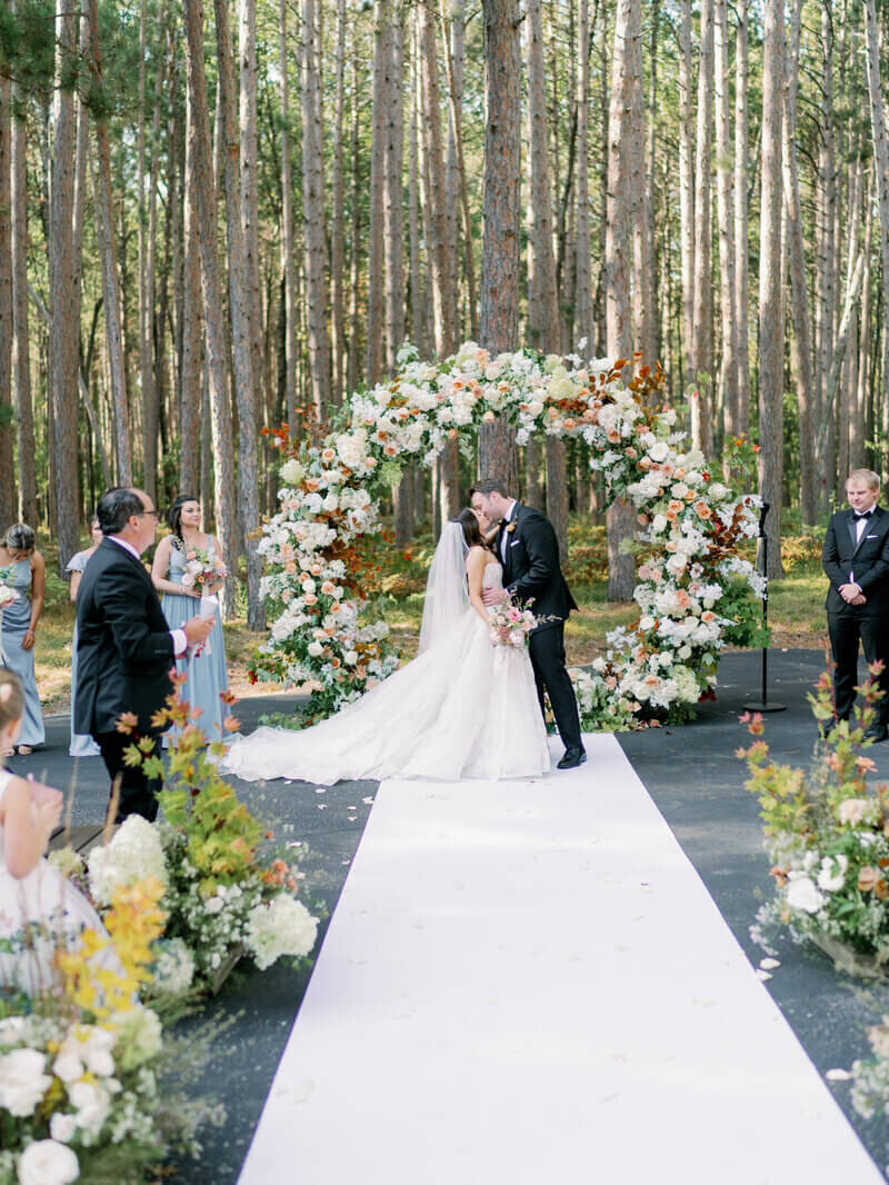 Bride and groom kissing in front of a floral arch by wedding planners chicago il