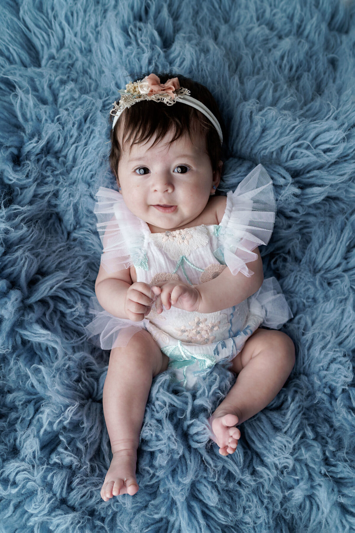 Baby Girl in Floral Embroidered Romper on Blue Flokatti