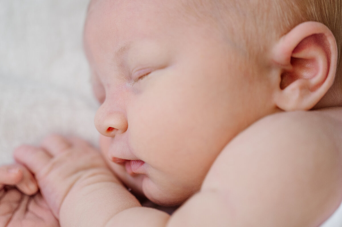 side profile of chubby newborn baby boy on white blanket by photographer harrisburg pa