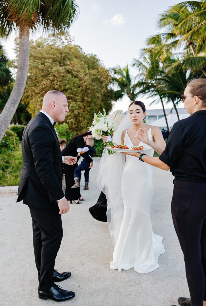 A candid moment of the bride and groom enjoying passed hors d’oeuvres during cocktail hour at their elegant outdoor wedding. Destination wedding photography by Claudia Amalia Photography.