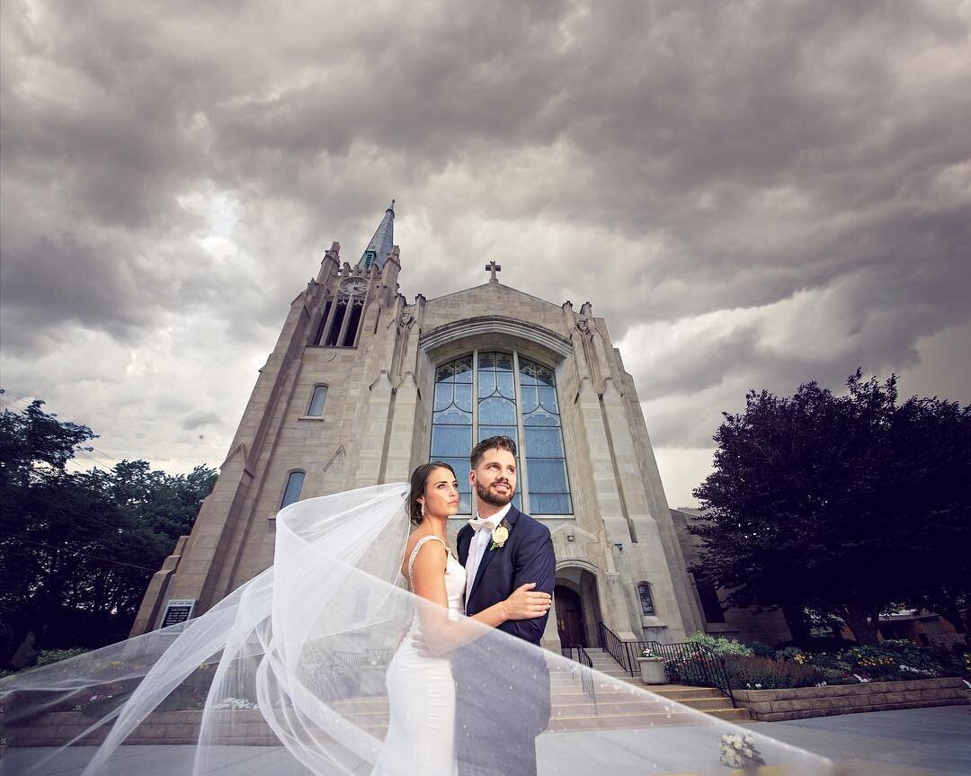 bride-and-groom-with-flowing-veil-in-front-of-cathedral-church