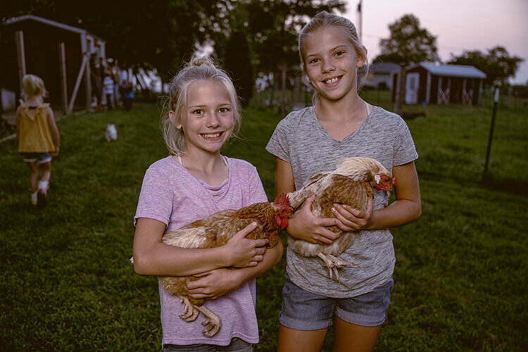 homestead sisters holding farm chickens