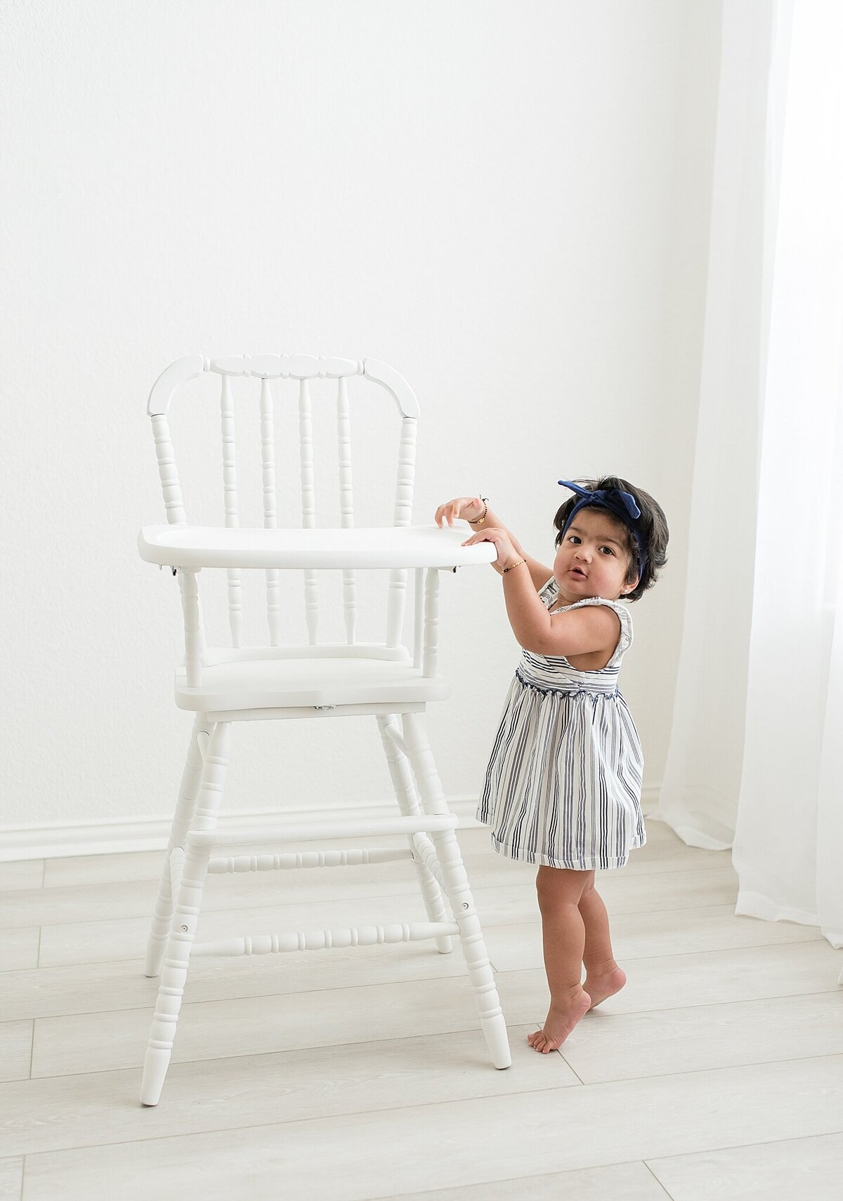 toddler standing next to vintage high chair
