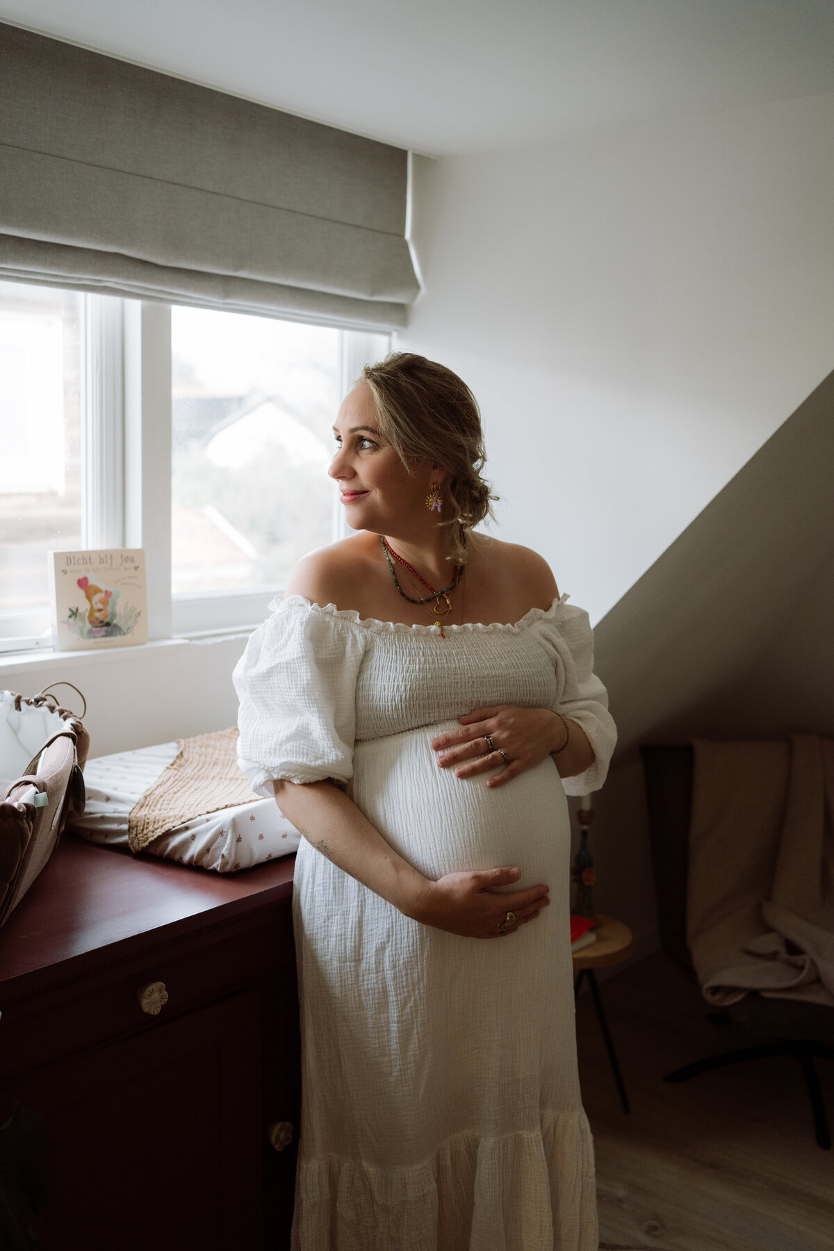 Sfeervolle zwangerschapsfoto van een vrouw met een prachtig zichtbare buik, vastgelegd in een warme en authentieke setting.