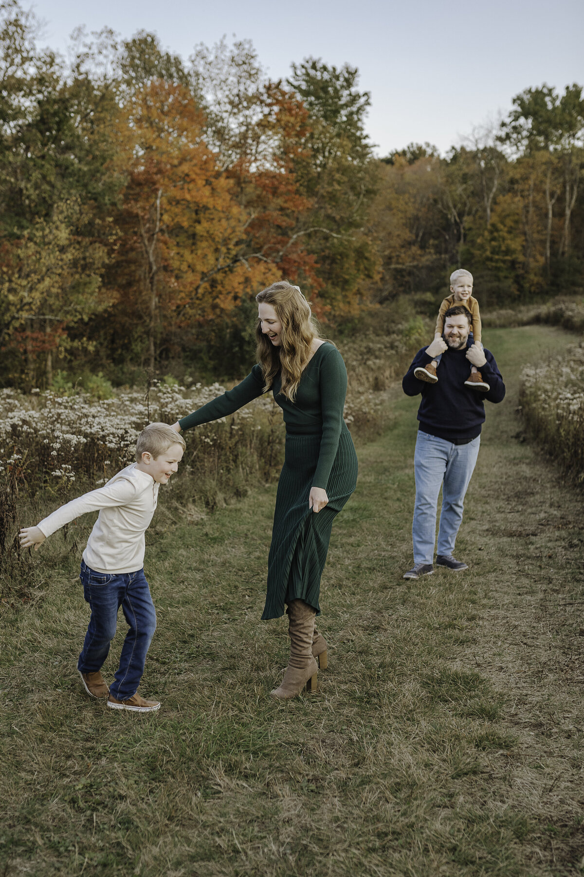 Verona B Photography captures a beautiful fall family photo of a mom, dad, and their two boys at Kendall Hills in Peninsula, OH. The family was having the best time being together, laughing, and dancing. The fall colors were really at peak color and the sun was perfect for this family photo session near Akron.