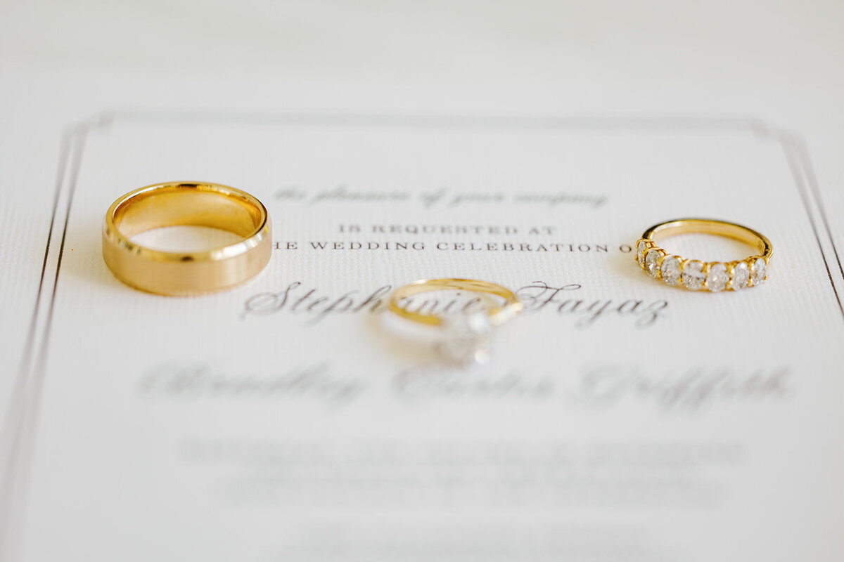 A close-up of the couple’s gold wedding bands and diamond engagement ring placed on top of their wedding invitation. A timeless detail shot from Stephanie and Bradley’s wedding in Islamorada, photographed by Claudia Amalia Photography.