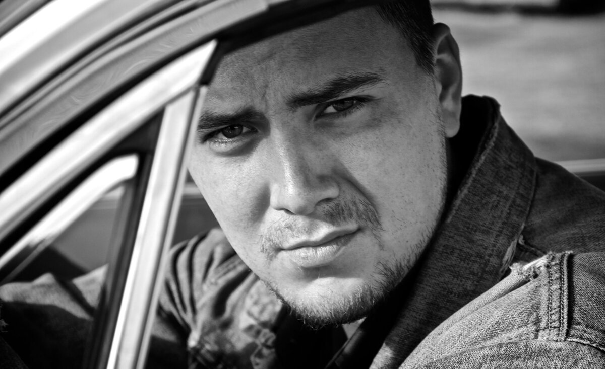 Male musician portrait Thompson Wilson black and white close up leaning against steering wheel inside old car