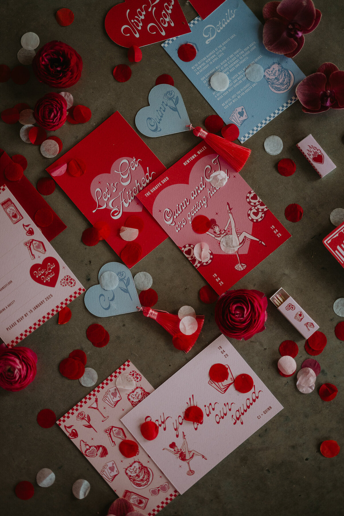 Pink and Red Las Vegas wedding stationery and confetti on a concrete floor at The Giraffe Shed. 