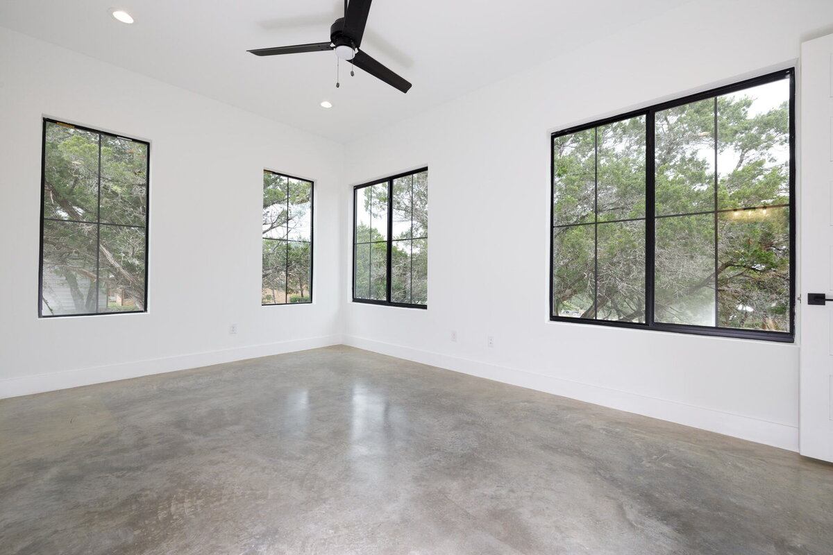 main bedroom with white walls, black windows and concrete floors