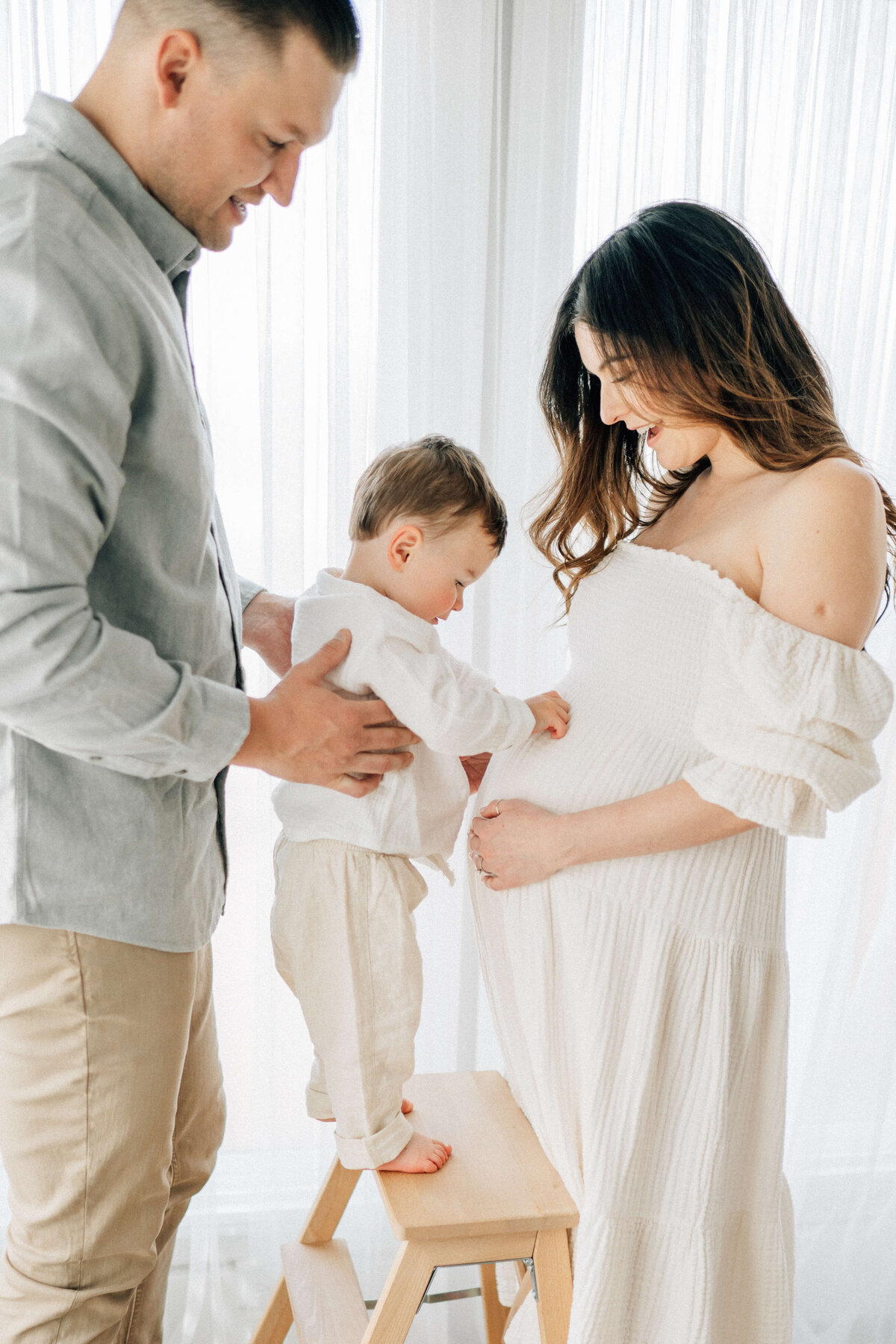 maternity mother looking at her son being held by his father