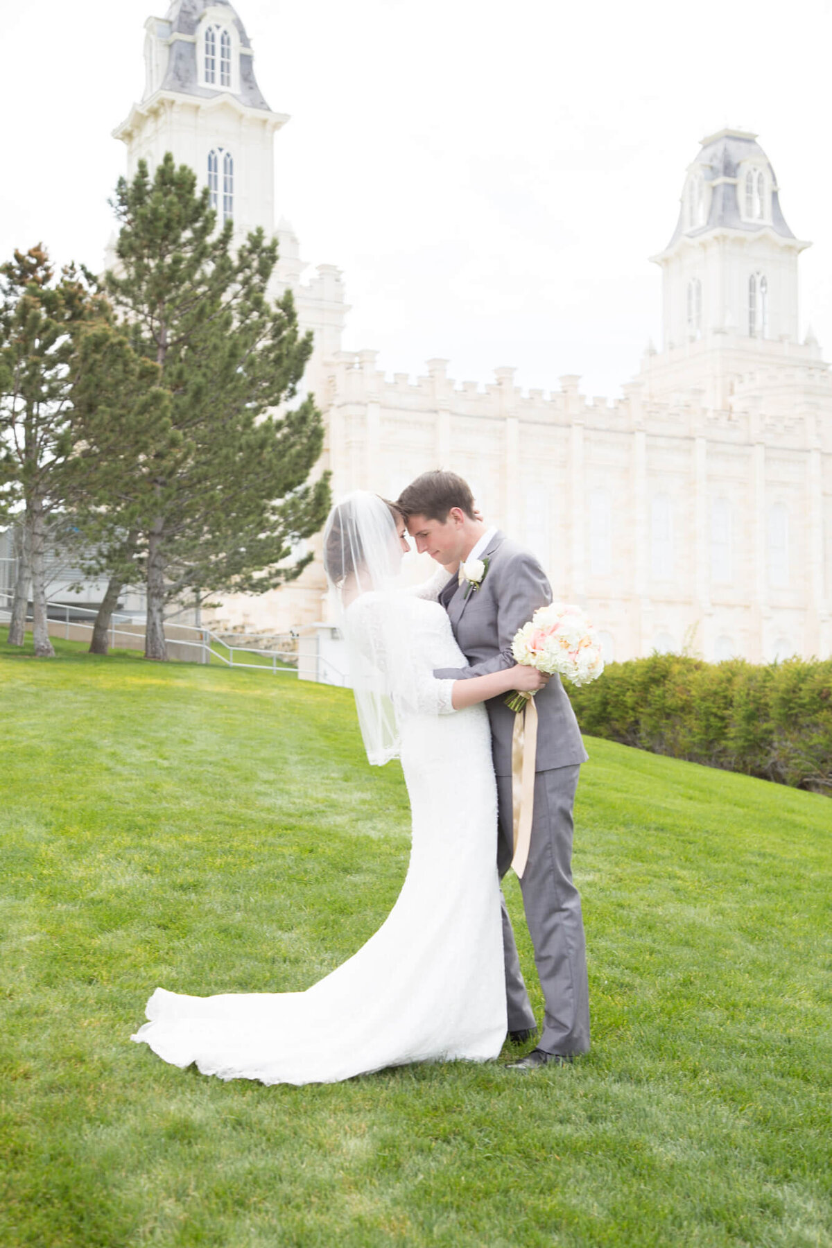 Bride and groom looking at each other with foreheads together in front of the Manti Utah lds temple