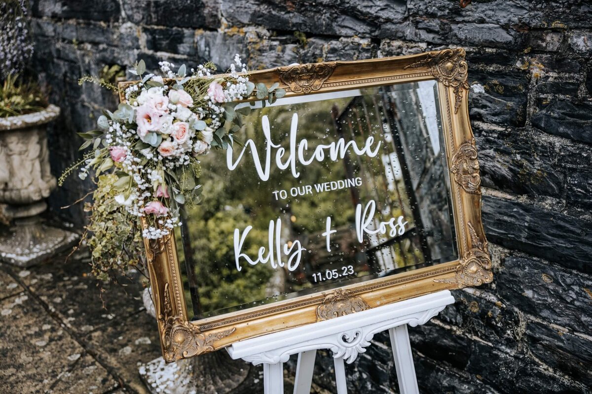 A welcome sign with flowers on top of it