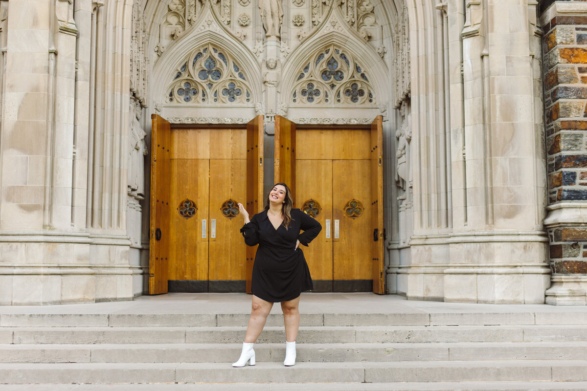 Candid photo of a graduate on the steps of their university campus.