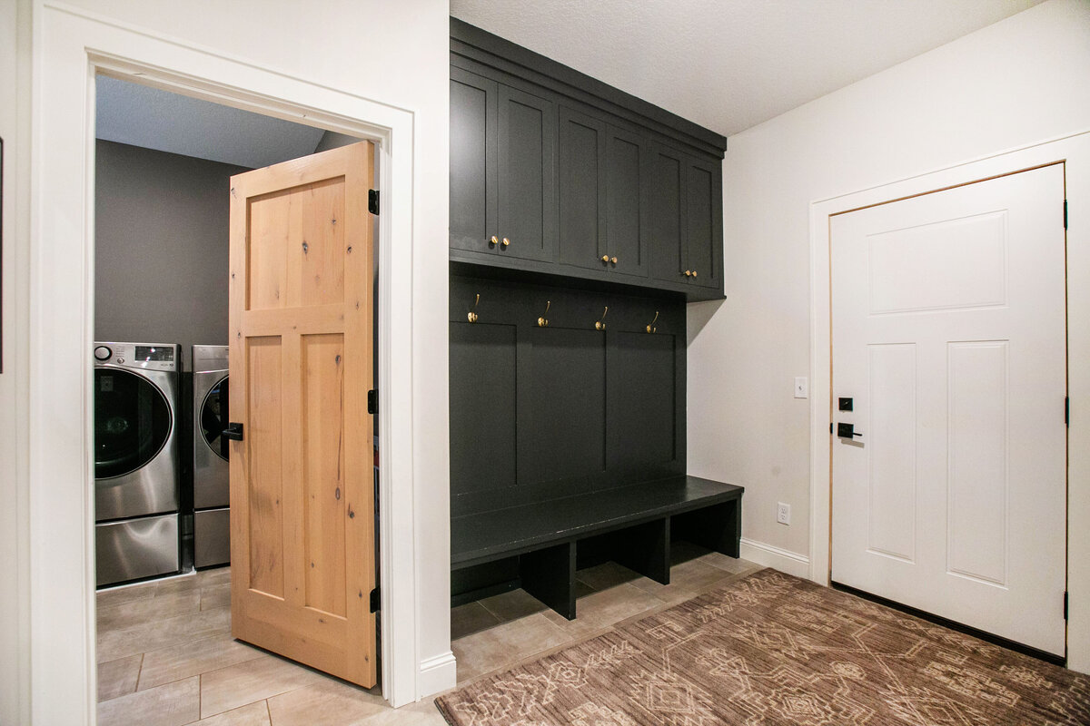 Custom mudroom with black lockers, wood flooring and neutral tones in a custom-built Otsego home