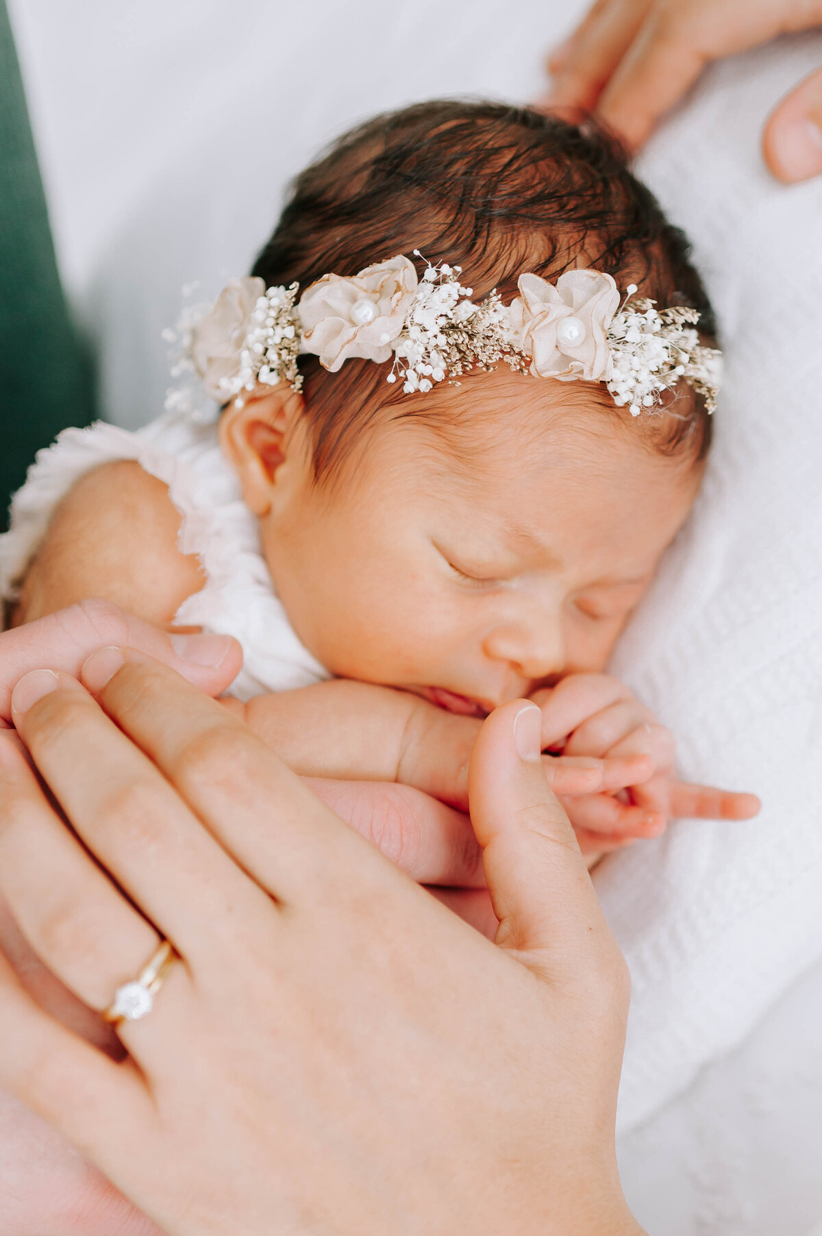 Springfield MO newborn photographer captures newborn baby laying down with parents hands holding her