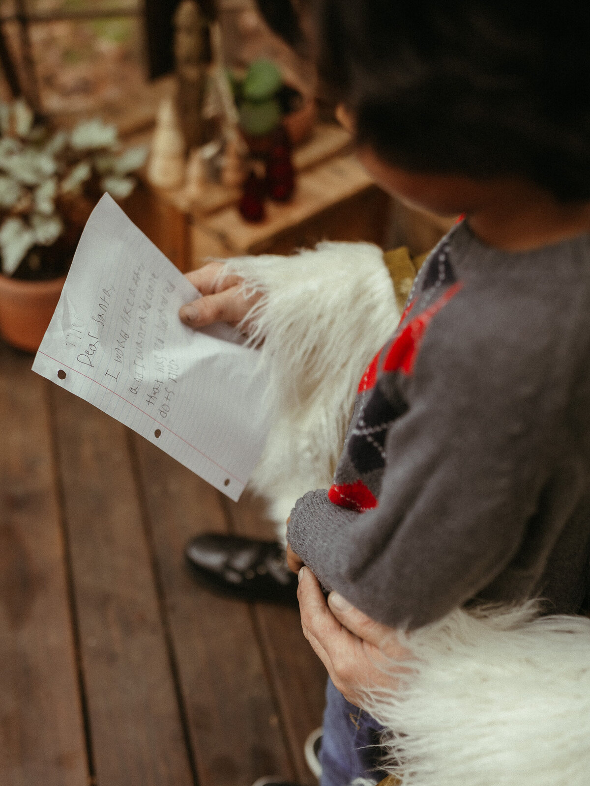 A child sitting on Santa's lap showing him their Christmas wish list. 