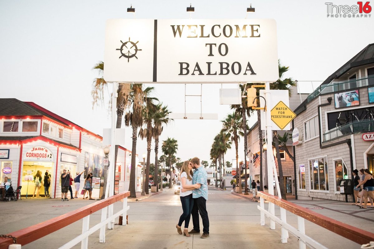 Engaged couple share a kiss at the ferry entrance to Balboa Island