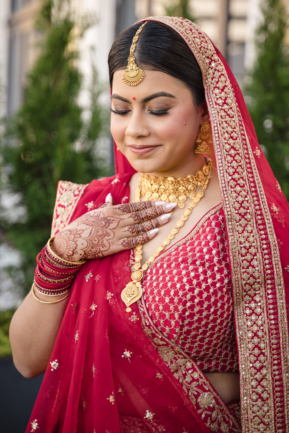 Indian bride in red and gold lehenga with traditional jewelry and henna, photographed at the Grand Bohemian Hotel Charlotte by a professional Indian wedding photographer in Charlotte. 