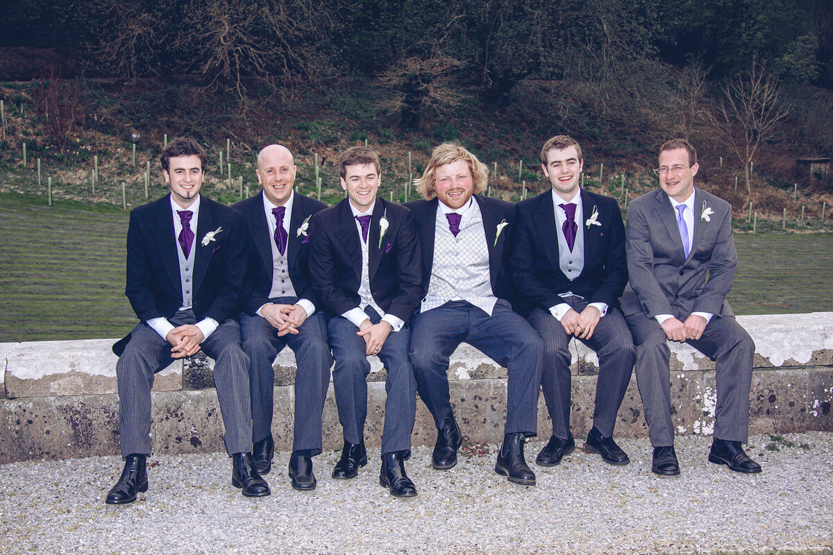 pro-story-photography_male-wedding-party-sat-on-wall_kitley-house_yealmpton_devon