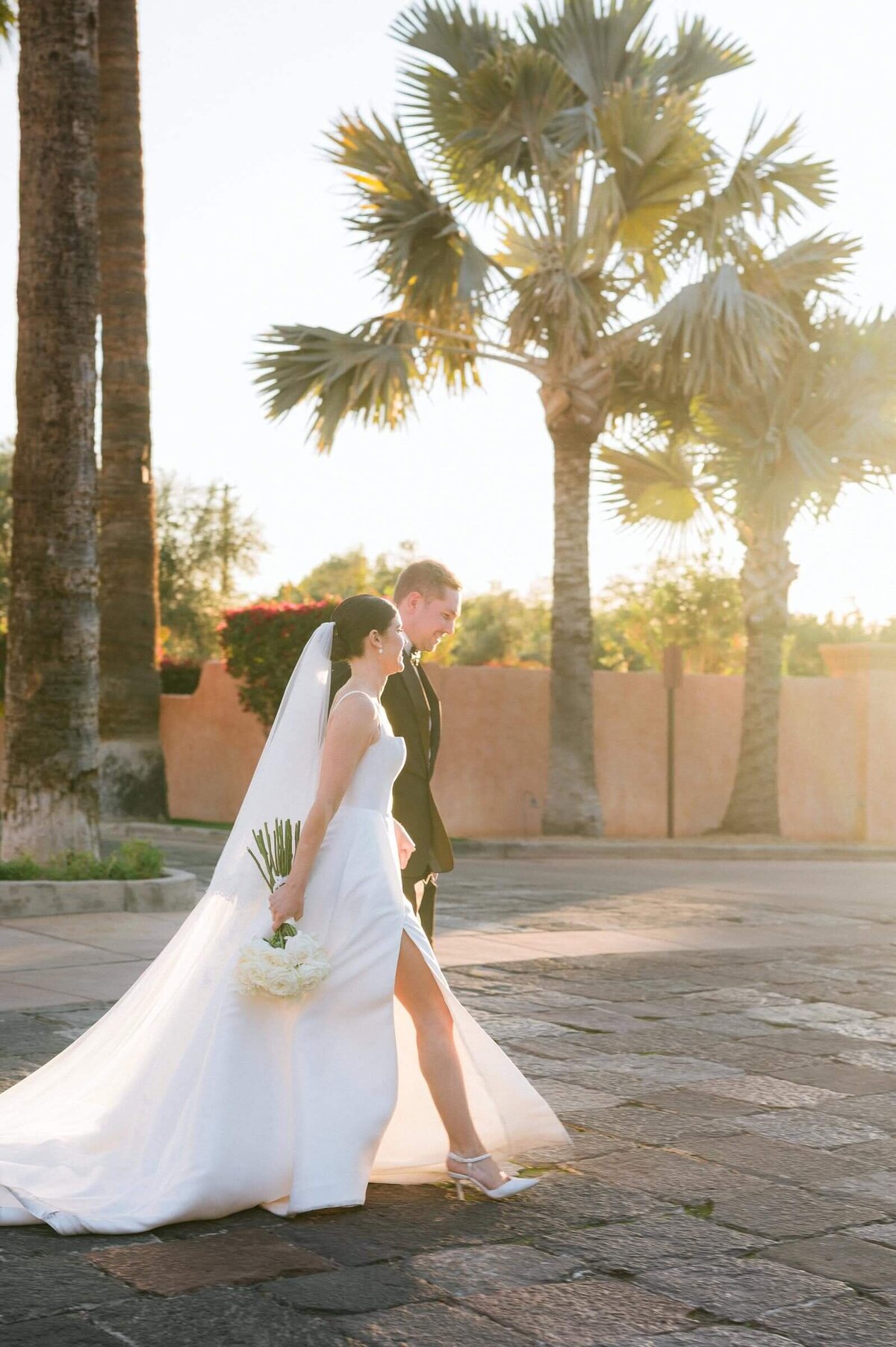 Bride and groom walking through the palm-lined courtyard at Royal Palms Resort in Phoenix, captured by Arizona wedding photographers.