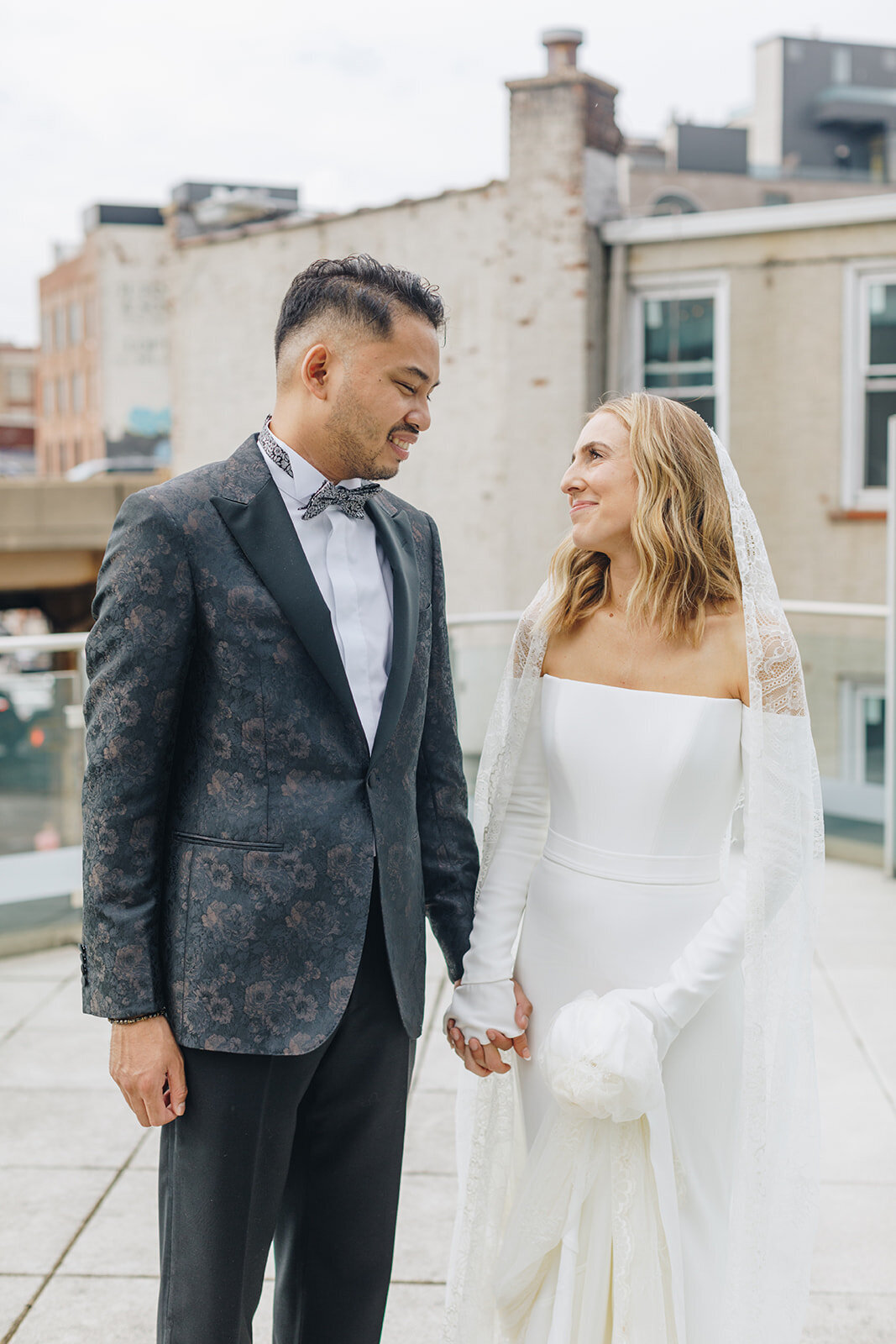 bride and groom holding hands and walking on a rooftop in NYC