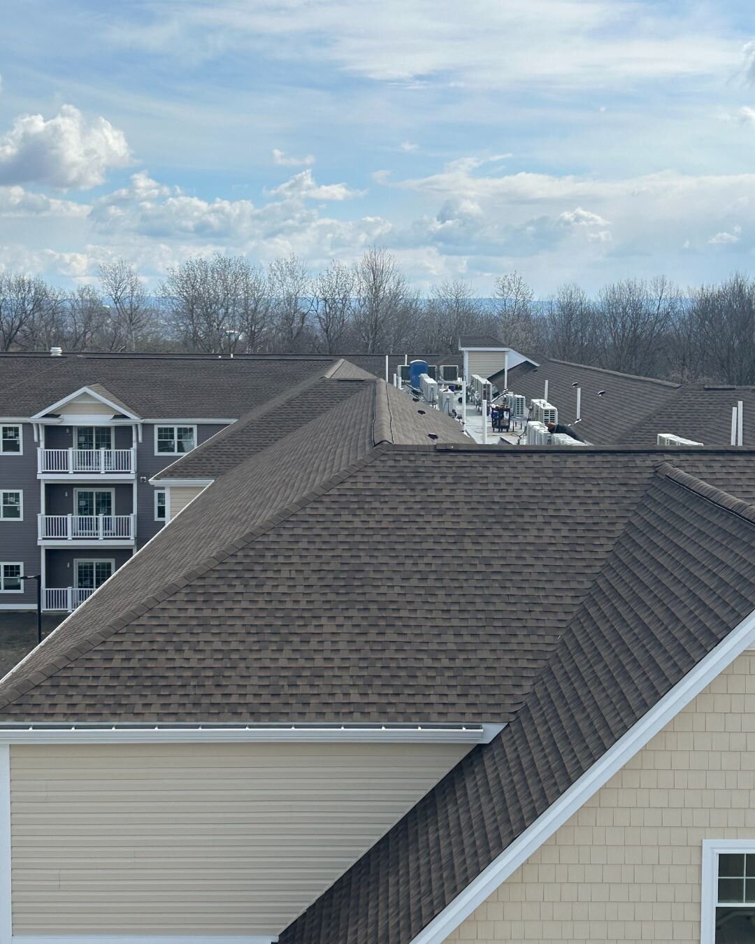 View of a commercial roofing project at an apartment complex with new brown asphalt shingles roofing