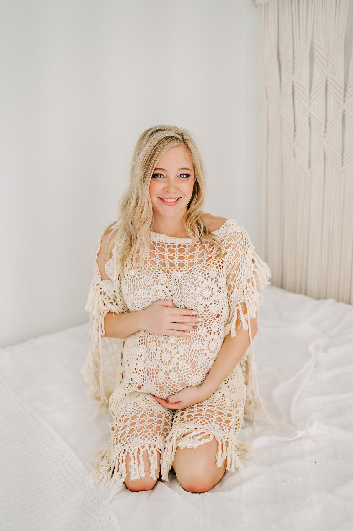 Springfield Mo maternity photographer The XO photography captures pregnant mom kneeling on bed hugging baby bump