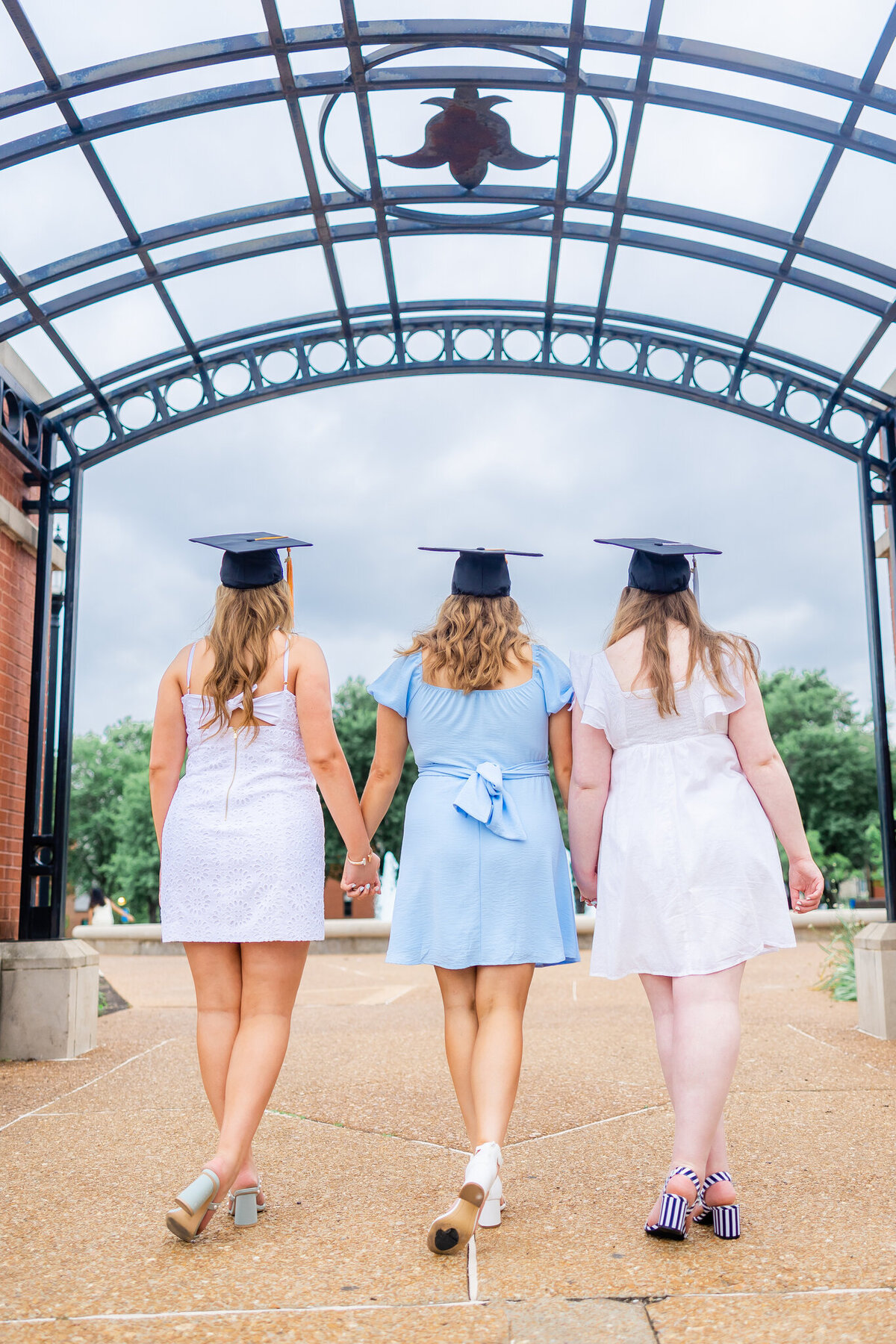 3 senior girls at SLU holding hands with backs towards the camera