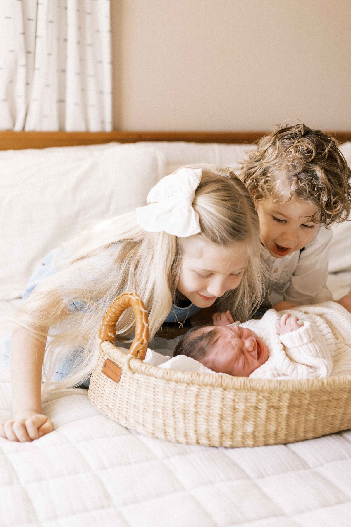 siblings looking at baby brother in basket during peoria illinois in home newborn baby photos 