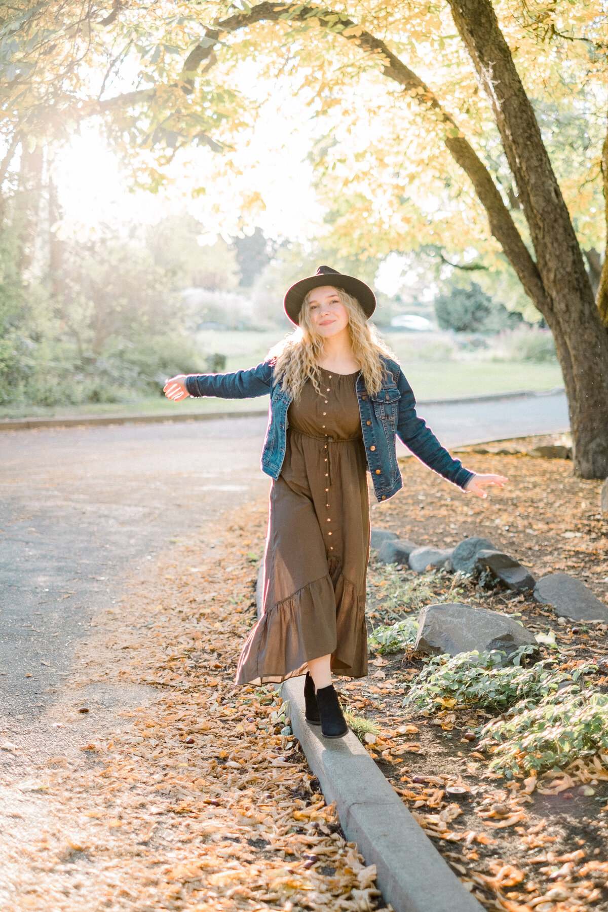 high school senior girl walking on curb towards camera wearing olive green dress taken by spokane senior photographer