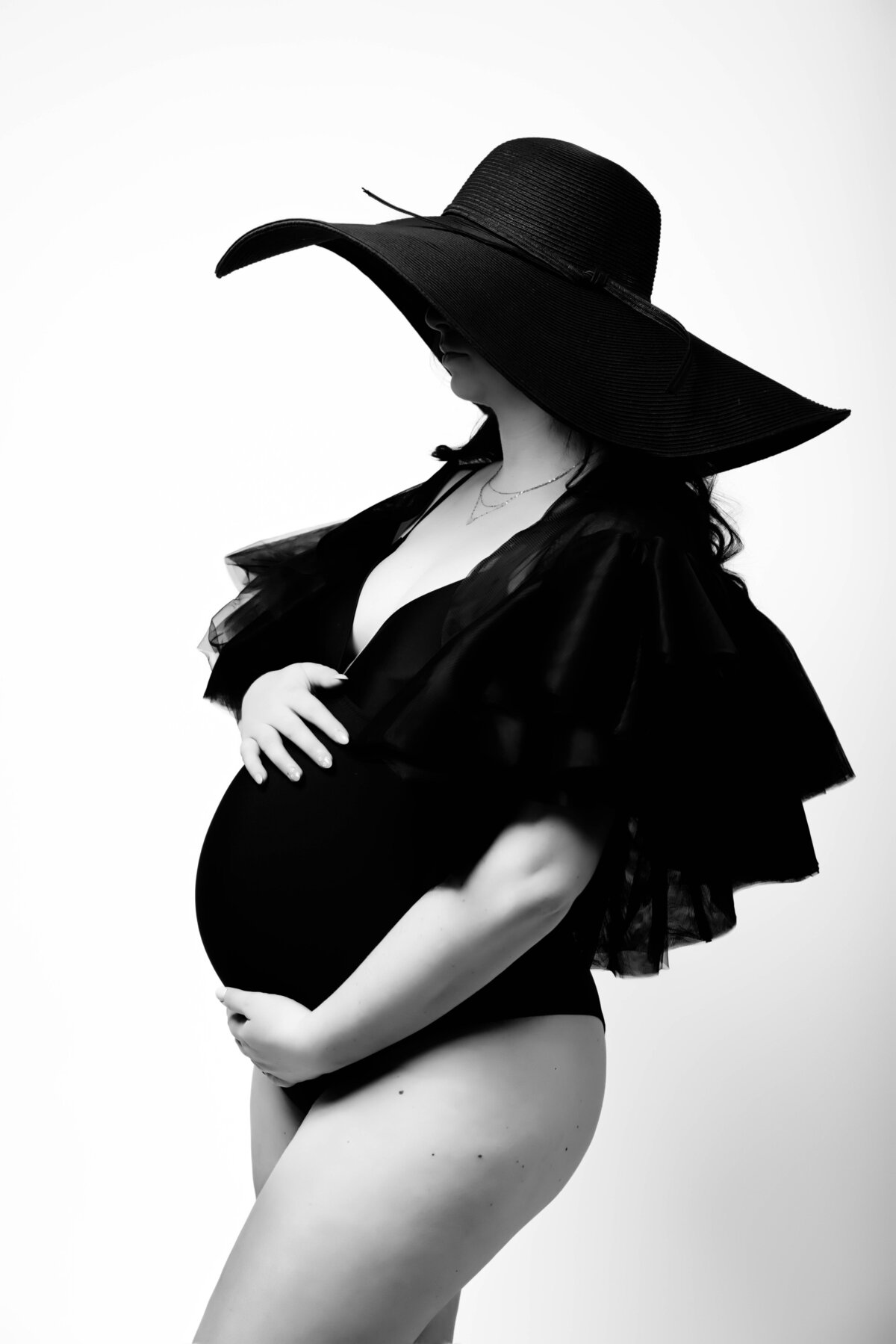 pregnant woman holding her belly in vogue fashion for maternity session with reva davis photography