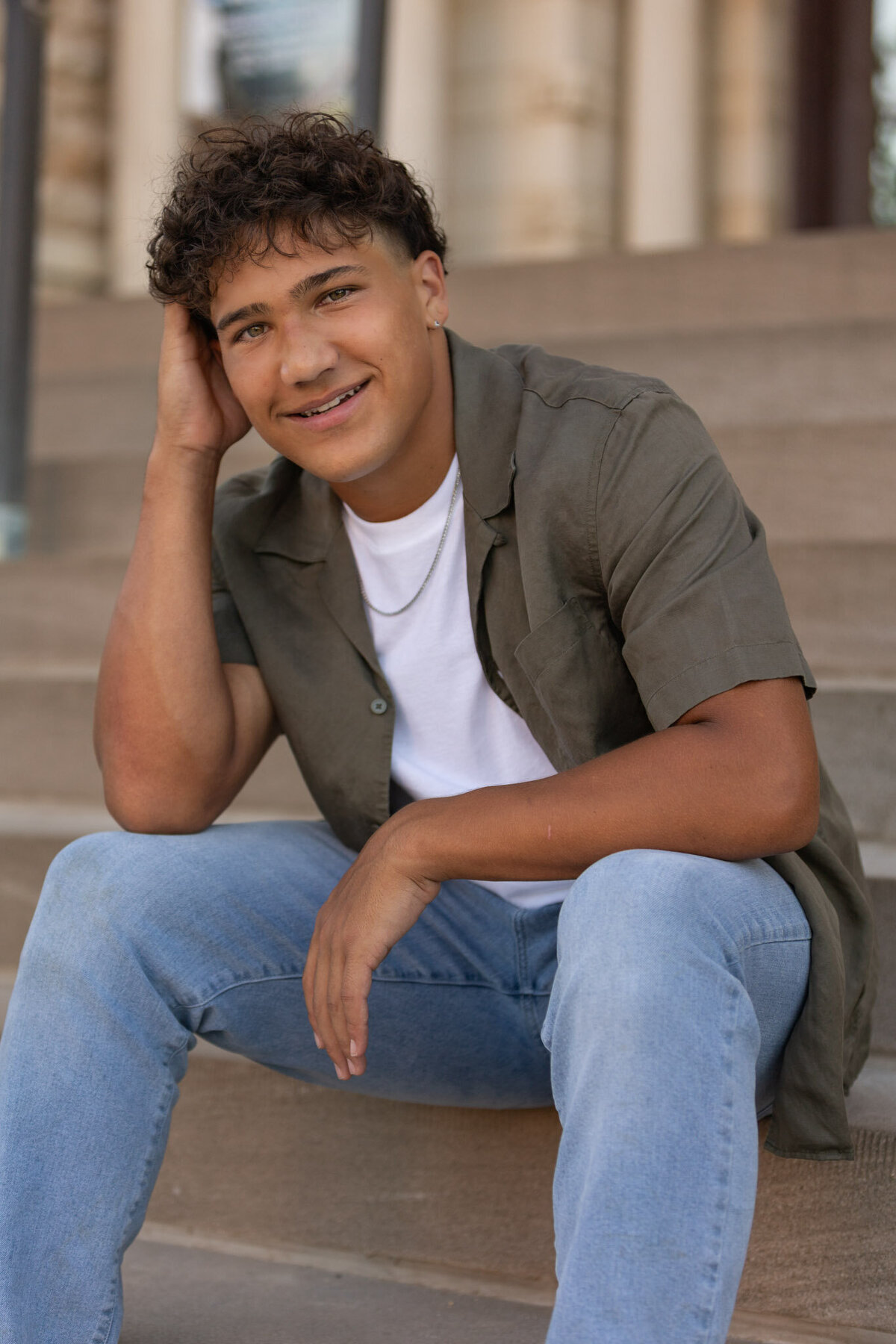 A senior guy sitting on concrete stairs leaning on his knees in Lawrence, KS