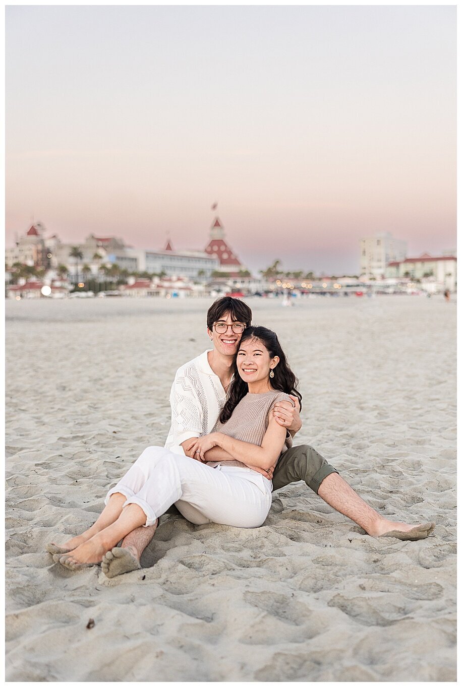 engaged couple sitting in sand at coronado san diego