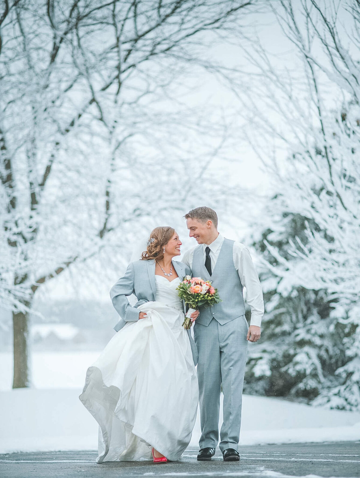 A bride and groom walking in the snow at their winter wedding with a Grand Rapids wedding photographer