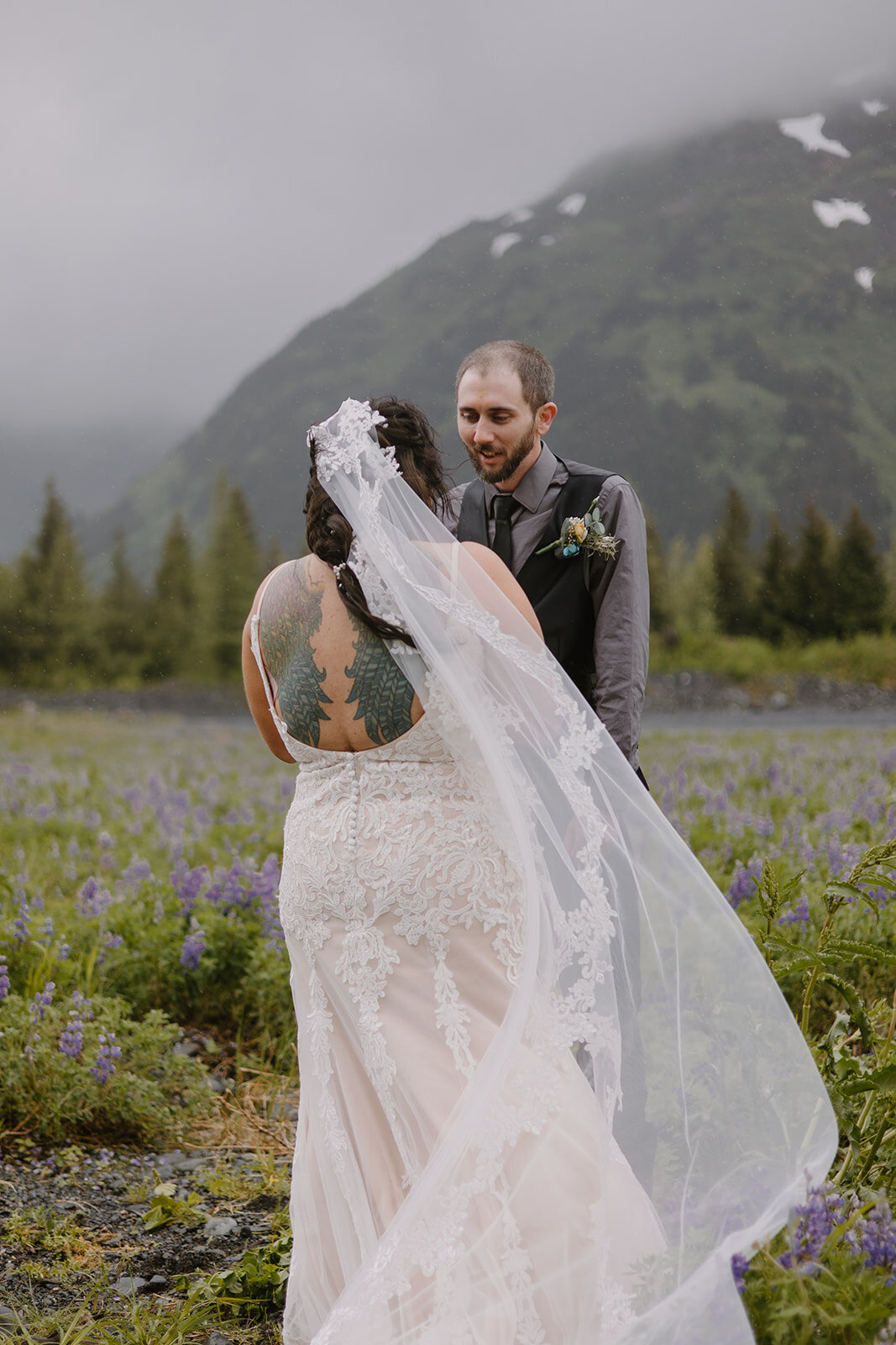 Elopement couple recites vows in flower field with mountain view.
