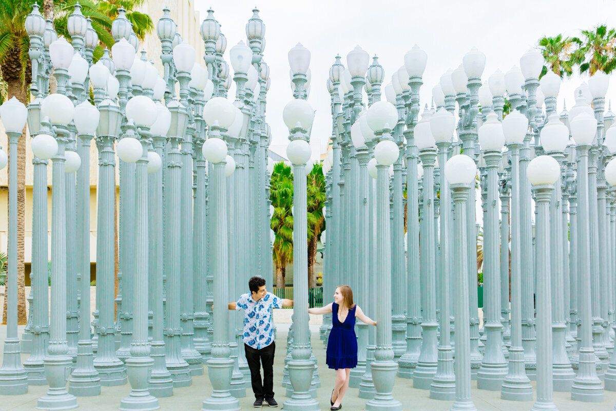 A couple walking through a plaza of light posts.