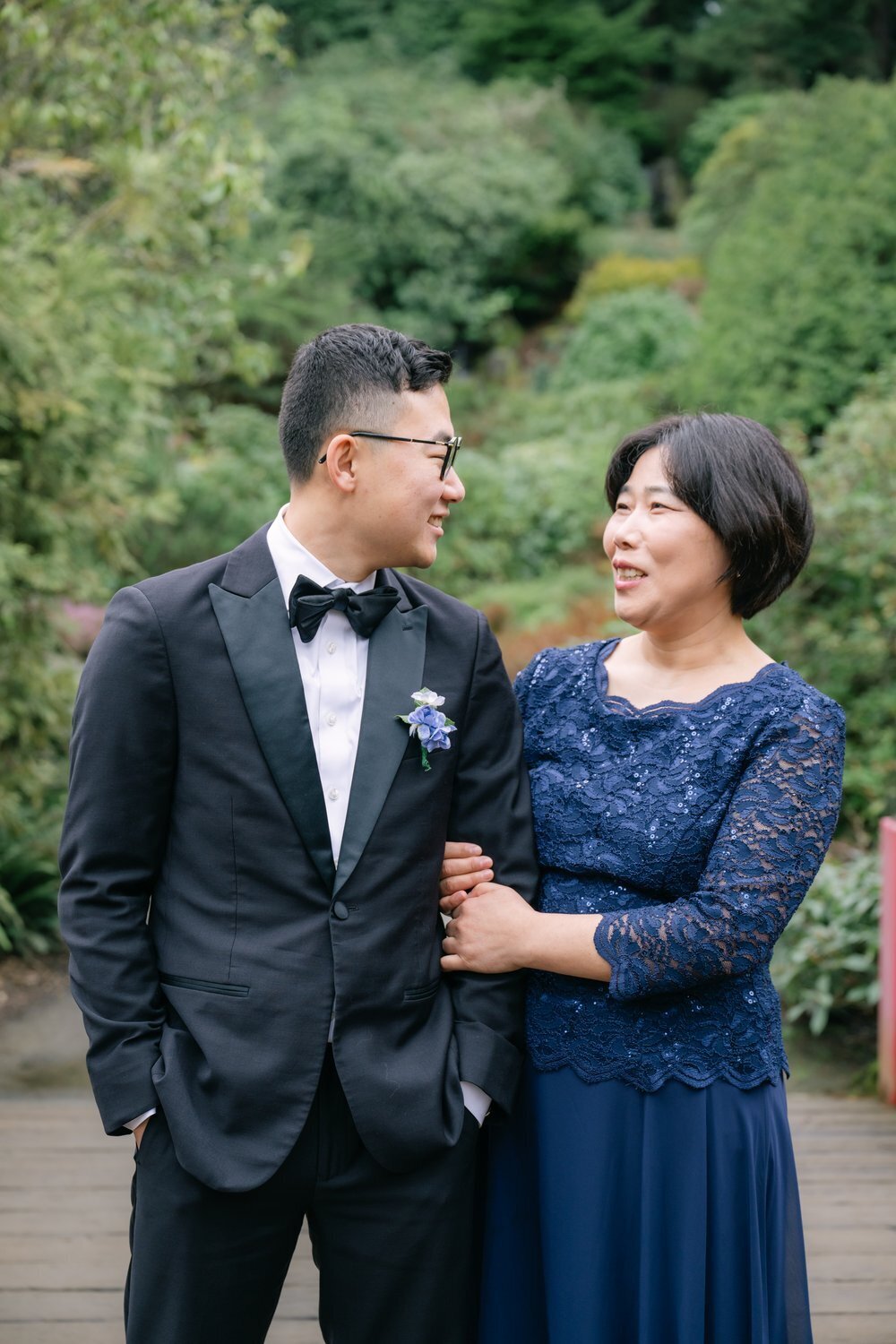 groom and mom pose for formal portrait in garden