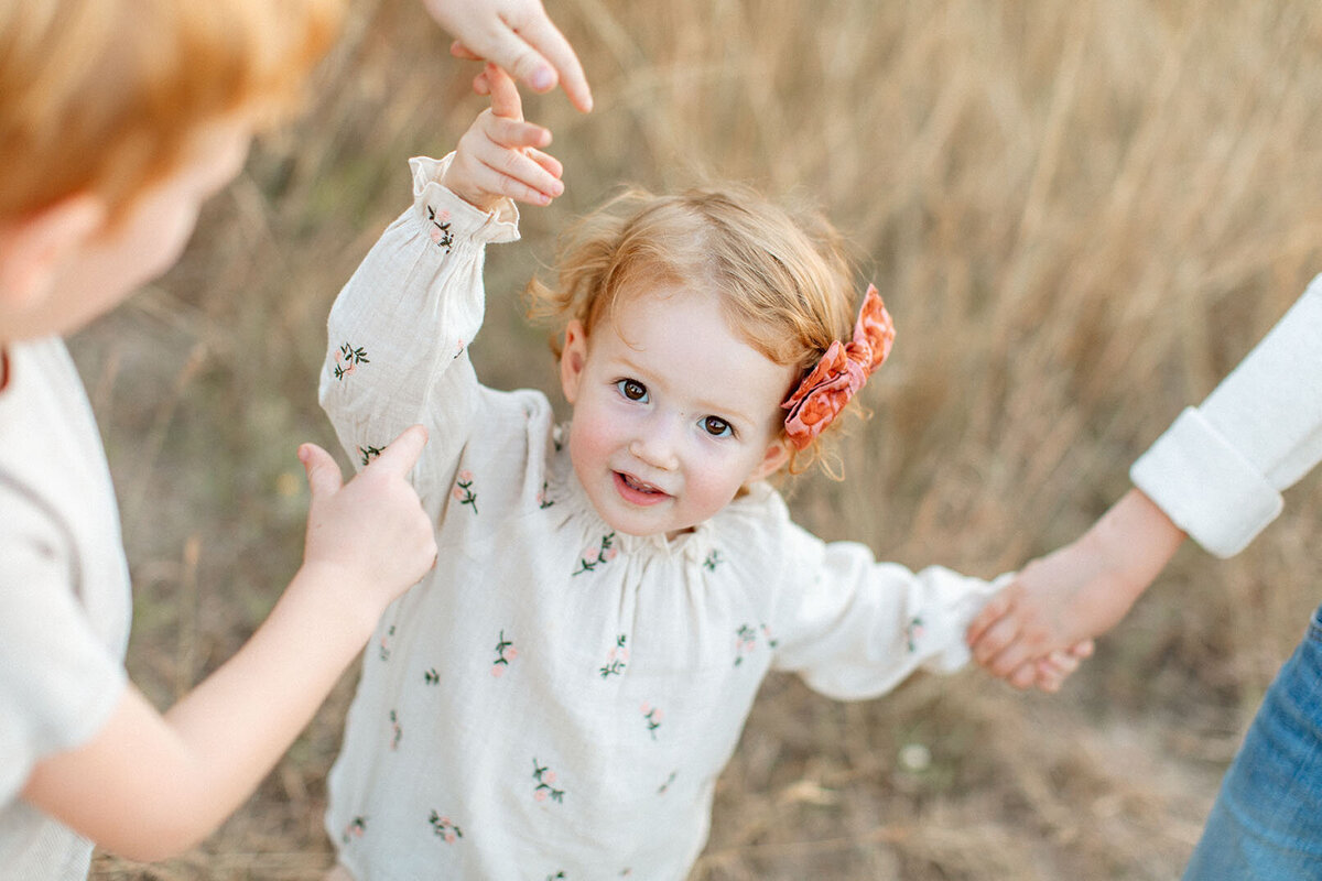 Children playing together in open field - Sara James San Antonio children's photographer captures childhood moments and sibling relationships during outdoor family sessions in Texas natural settings