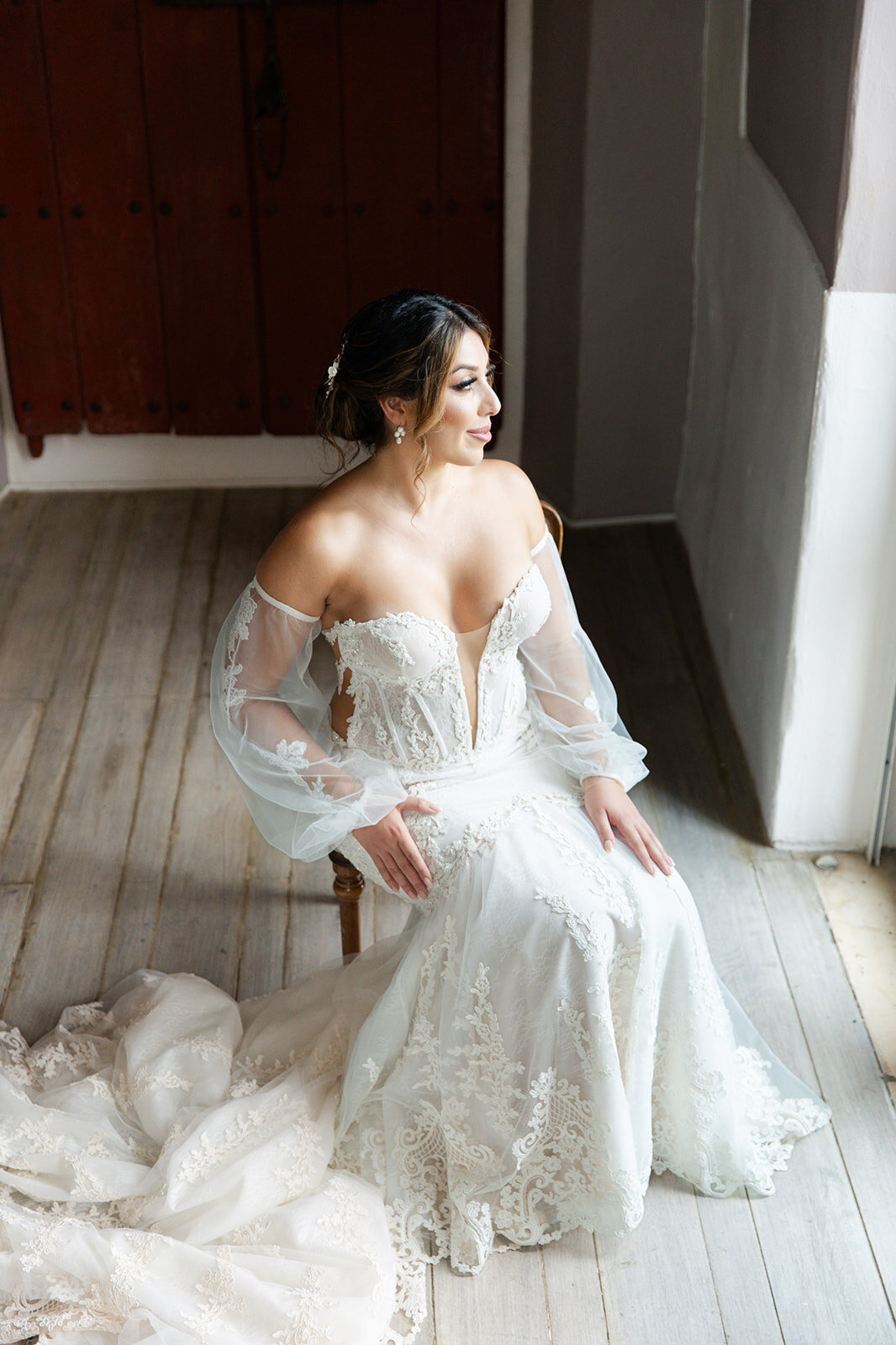 Victoria sits elegantly in her lace off-the-shoulder wedding gown, soaking in the moment before her Cartagena Colombia wedding.