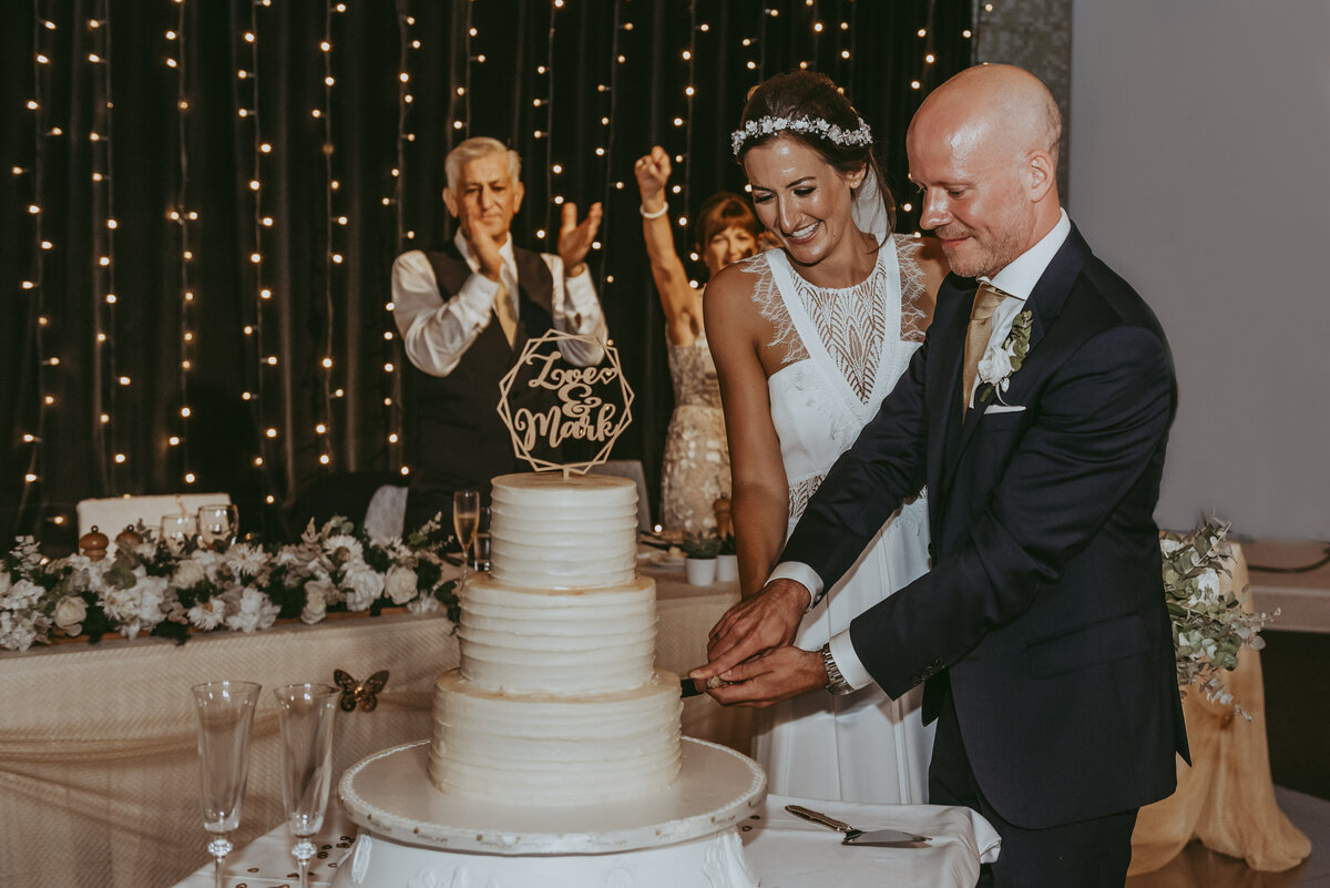 Bride & Groom cutting a three tier wedding cake at their reception