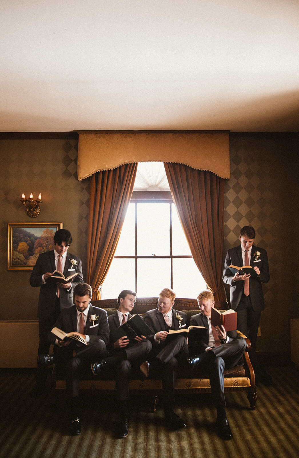 groomsmen pose on a couch in a library