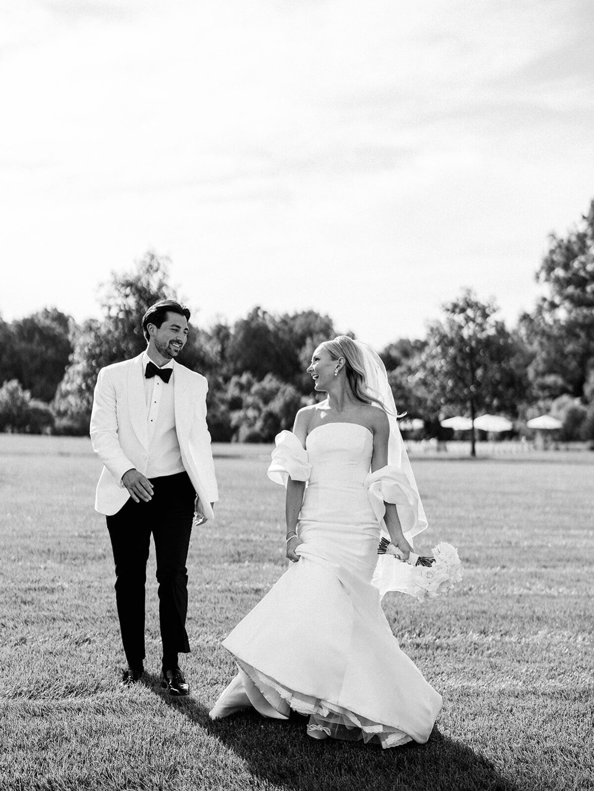 Bride and groom run in a field as they look towards each other 