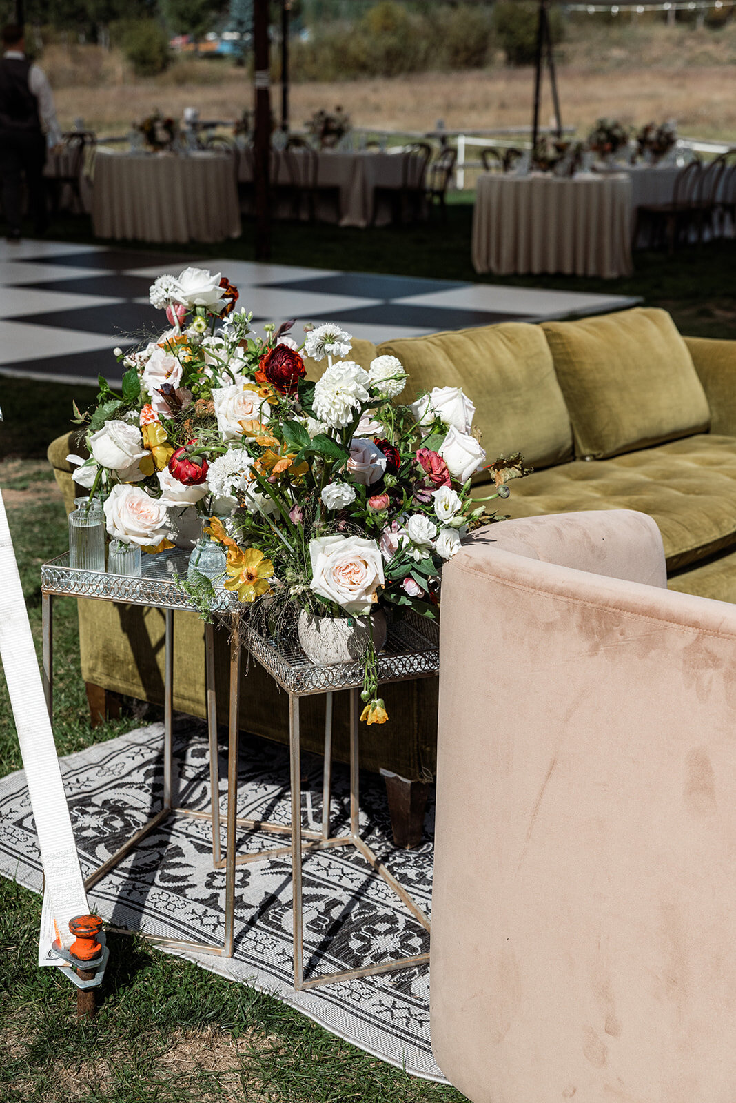 Details of the lounge area at a wedding including a couch and flowers on side tables.