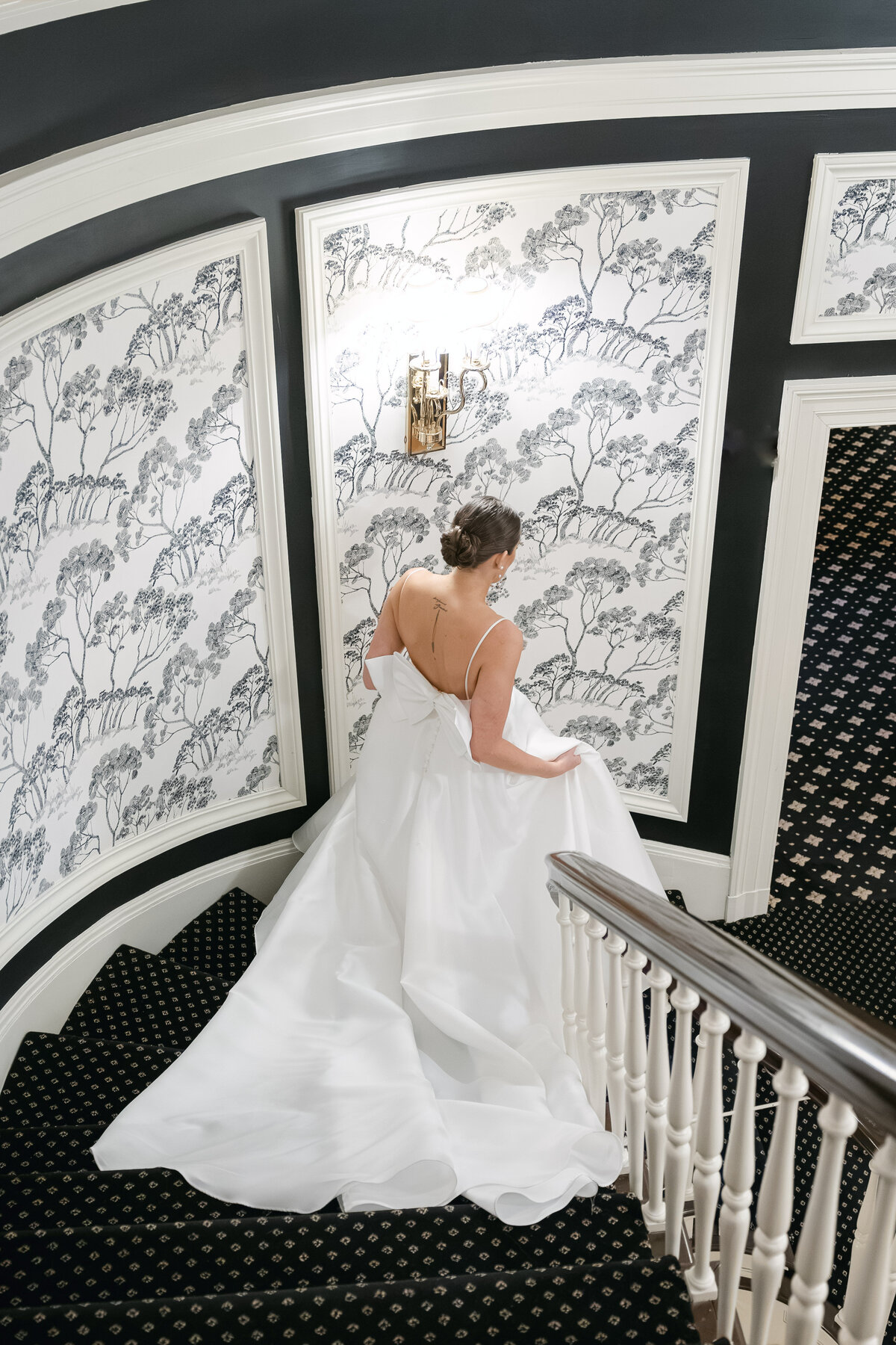 The bride gracefully walks down the stairs at The Madison Club, captured in a stunning solo portrait that highlights her beauty and elegance on her wedding day.