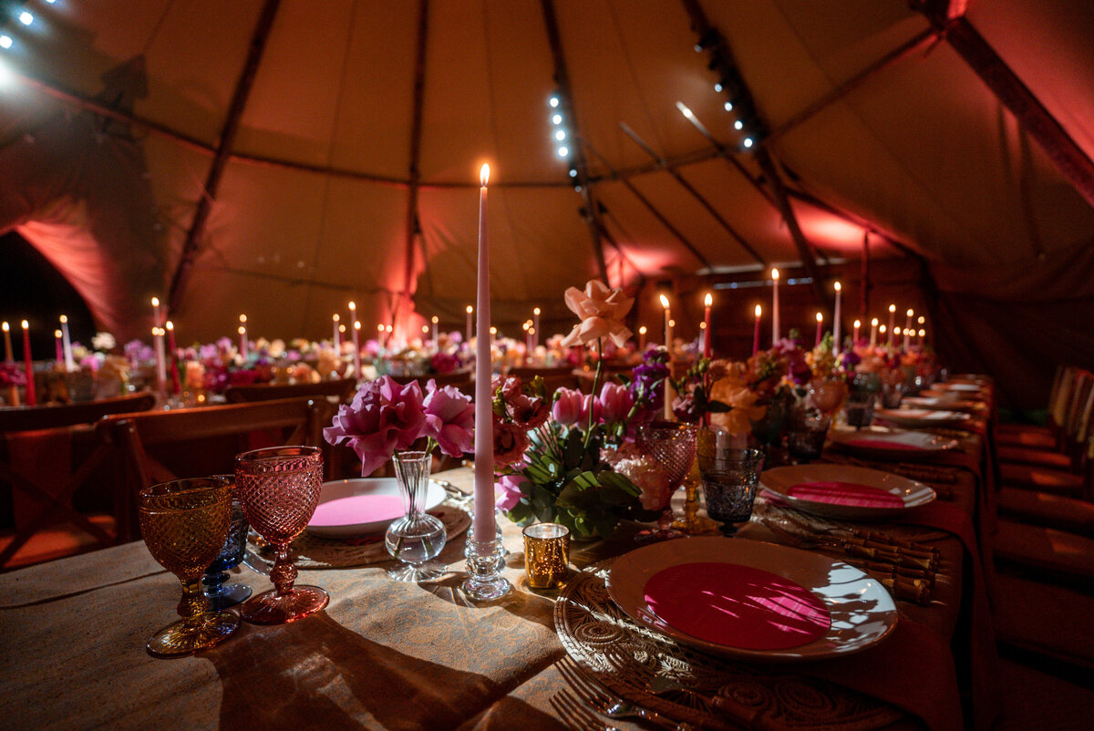 A teal, gold and pink dinner table is set for a party or wedding.