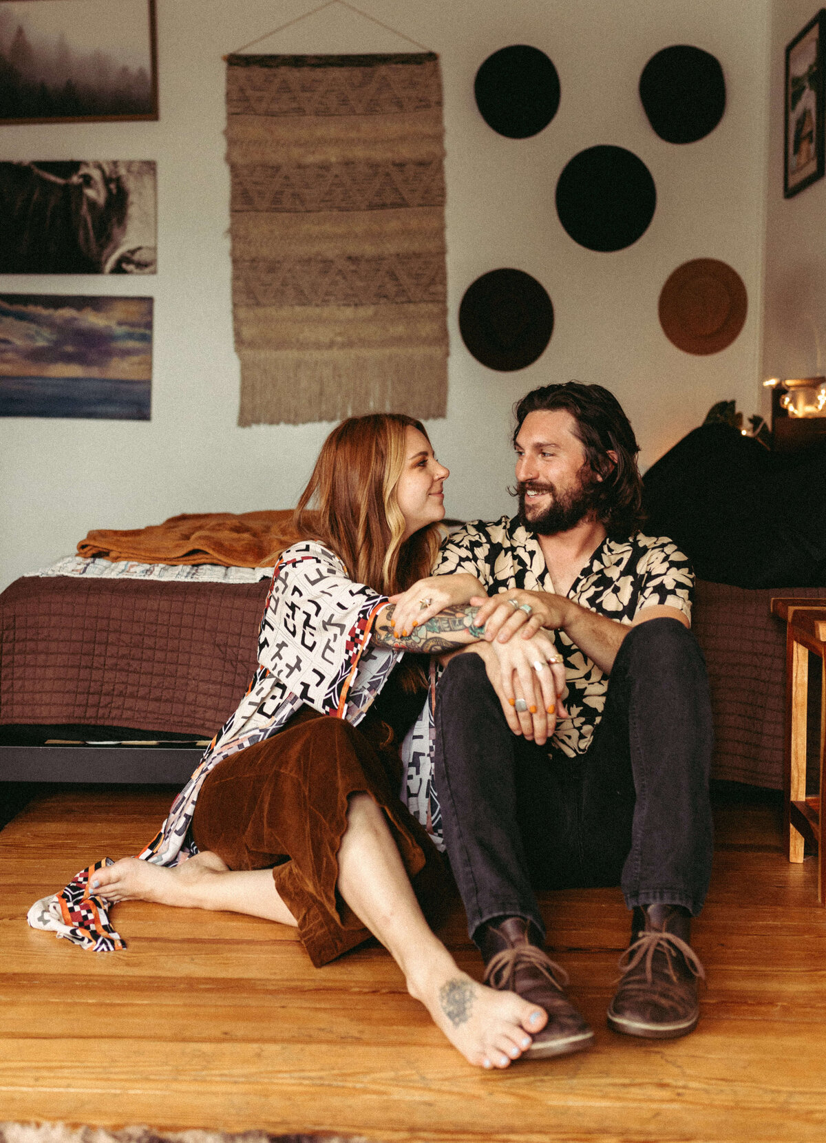 couple cuddling on floor near bed in engagement in-home session in panama city