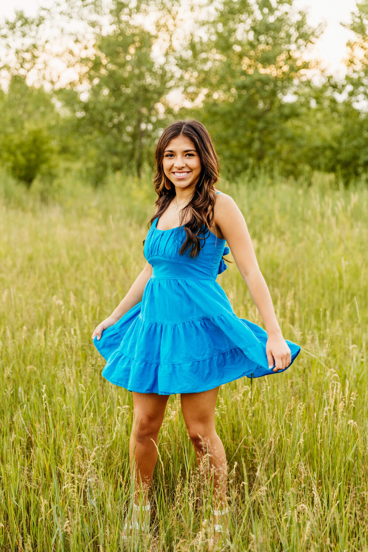 teenage girl spinning in her short blue dress and enjoying her senior photography session with Ashley Kalbus Photography