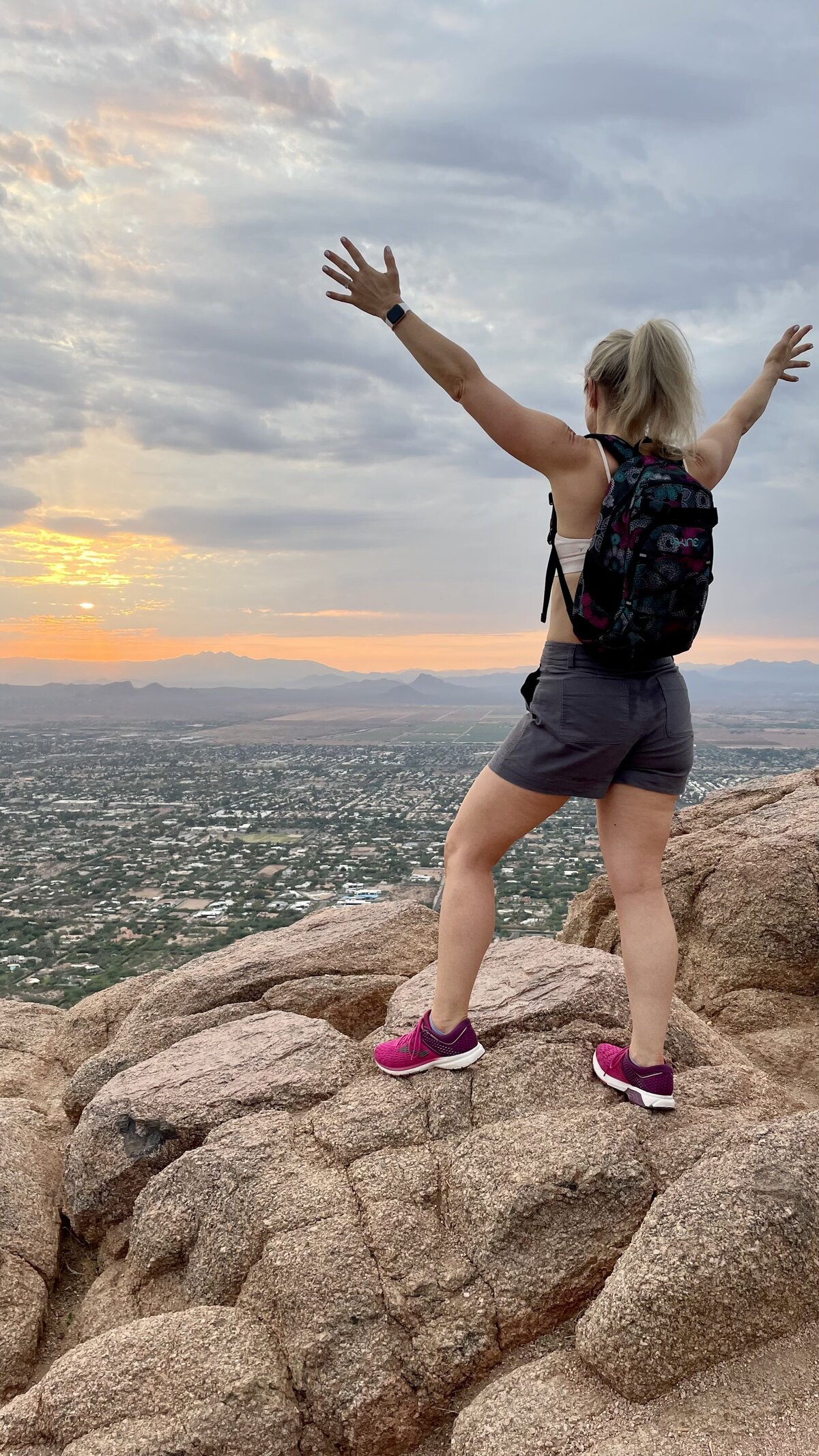 Ashley Malik standing on top of mountain surise sunrise with arms in the air
