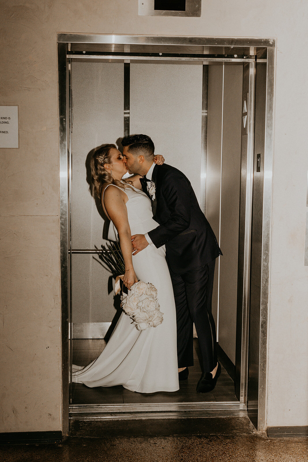 bride and groom kissing in an elevator